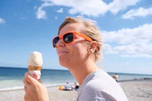 A woman eating an ice cream cone on the beach
